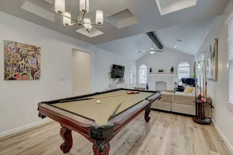 Game room with pool table, colorful abstract wall art, and beige sectional sofa near the fireplace at Capital Manor, Oklahoma City