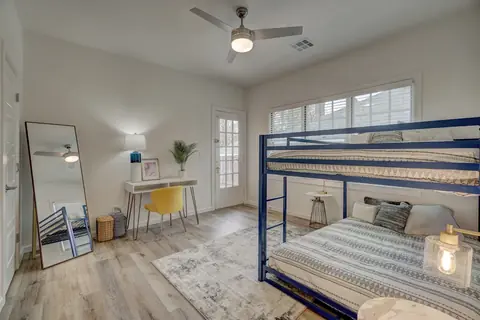 Bedroom with navy metal bunk bed, writing desk with yellow chair, full-length mirror, and ceiling fan at Capital Manor, Oklahoma City