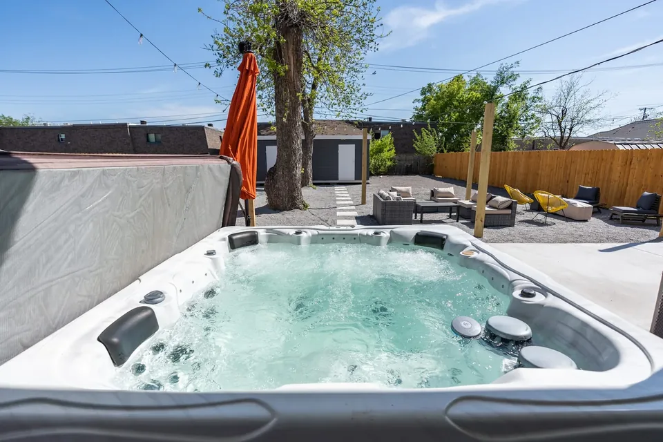 Bubbling backyard hot tub at Classen Manor with lounge seating and string lights