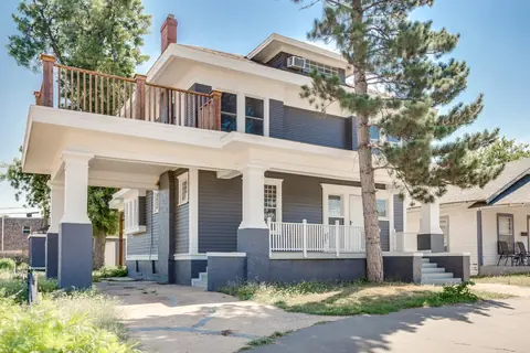 Historic two-story home with gray siding, white columns, covered front porch and second-floor deck at Classen Manor, Oklahoma City