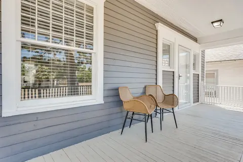 Covered front porch with two woven wicker chairs beside a large multi-pane window at Classen Manor, Oklahoma City