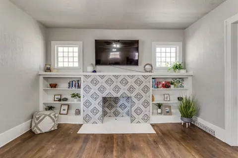 Patterned tile fireplace flanked by white built-in shelves stocked with books and board games at Classen Manor, Oklahoma City