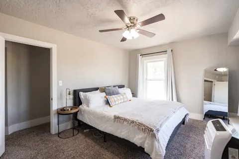 King bedroom at Classen Manor with ceiling fan, floor mirror and portable AC