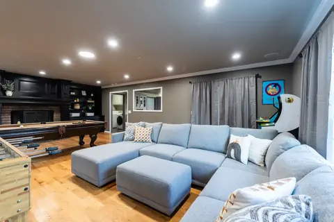 Lounge area with large gray sectional and ottomans beside a pool table, foosball table, and black built-in fireplace at Gaillardia Manor, Oklahoma City