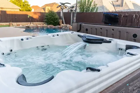 Bubbling hot tub with waterfall feature overlooking the backyard pool at Gaillardia Manor, Oklahoma City