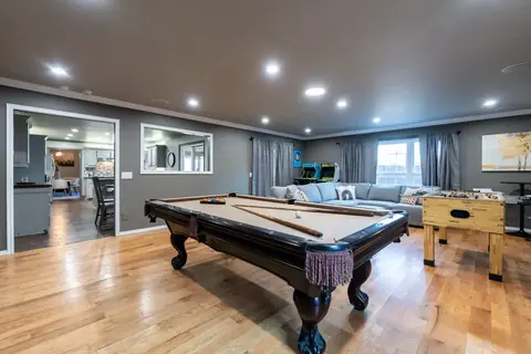 Game room with pool table, foosball table, retro arcade cabinets, and gray sectional sofa at Gaillardia Manor, Oklahoma City