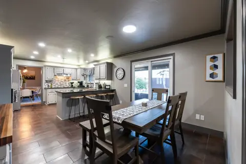 Kitchen with breakfast bar seating and wood dining table beside a sliding glass door overlooking the backyard pool at Gaillardia Manor, Oklahoma City