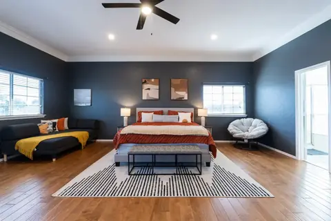 Spacious primary bedroom with king bed, navy walls, lounge sofa, papasan chair, and ensuite bath at Gaillardia Manor, Oklahoma City