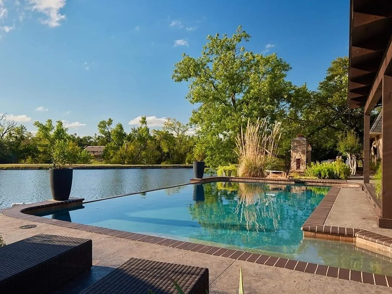 Infinity-edge pool spilling into the lake at Lakefront Manor — BnB OKC's flagship Oklahoma City vacation rental