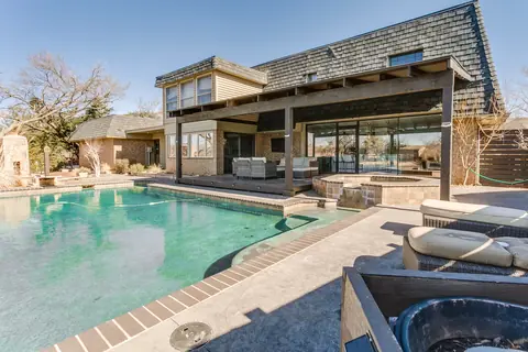 Backyard swimming pool and raised hot tub beside the covered patio and glass-walled rear facade at Lakefront Manor, Oklahoma City