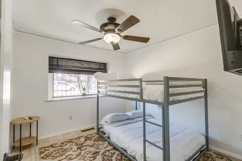 Bunk bedroom with full-size bunks, wall-mounted TV, and a window seat view at Lakefront Manor, Oklahoma City