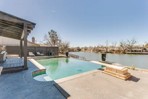 Infinity-edge pool overlooking Twin Lakes with a pergola-covered lounge deck at Lakefront Manor, Oklahoma City