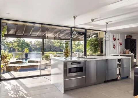 Glass-walled chef kitchen at Lakefront Manor with marble island and lake views