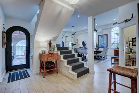 Entry foyer with carpeted staircase, arched glass front door and sightline into the dining room at Lakeside Manor, Oklahoma City