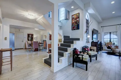 Open-concept living and dining area with carpeted staircase, folk-art painting, TV lounge and wood-look tile floors at Lakeside Manor, Oklahoma City