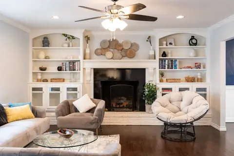 Living room with white built-in bookshelves, fireplace, velvet sofa and papasan chair at Quail Creek Manor, Oklahoma City