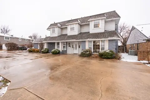Two-story gray and white home exterior with wide concrete driveway and a light dusting of snow at Quail Creek Manor, Oklahoma City