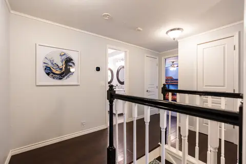 Upstairs landing with black and white staircase railing opening to bedrooms and a double-mirror bathroom at Quail Creek Manor, Oklahoma City