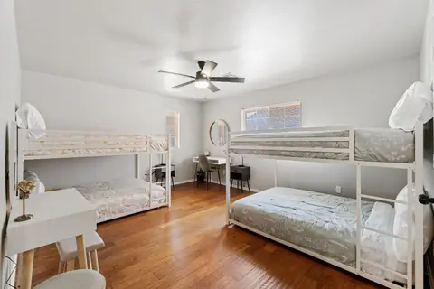 Bunk room with two bunk beds, a white desk with stools, and a round mirror vanity nook at Remington Manor, Oklahoma City