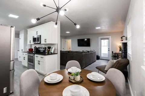 Open kitchen and dining at The Village Manor — round wood table under a sputnik chandelier